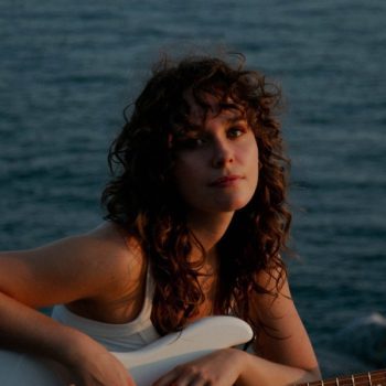 singer maude from canada holding a guitar with ocean view